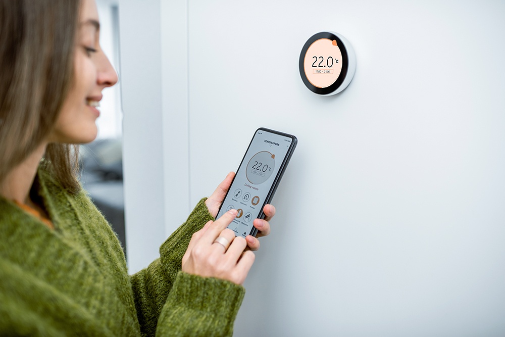 Woman manages wifi smart thermostat with her phone